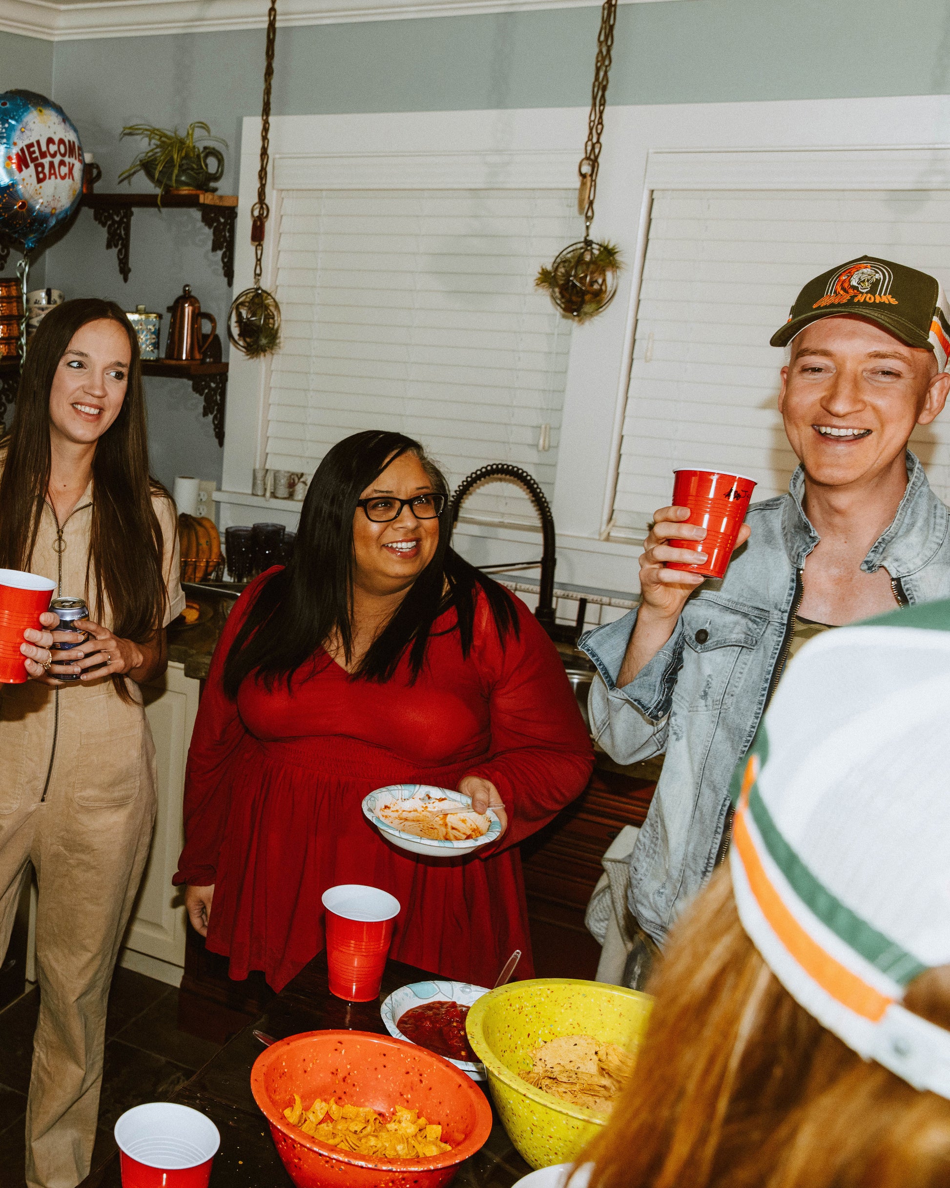 friends gathered in the kitchen, featuring come home hat