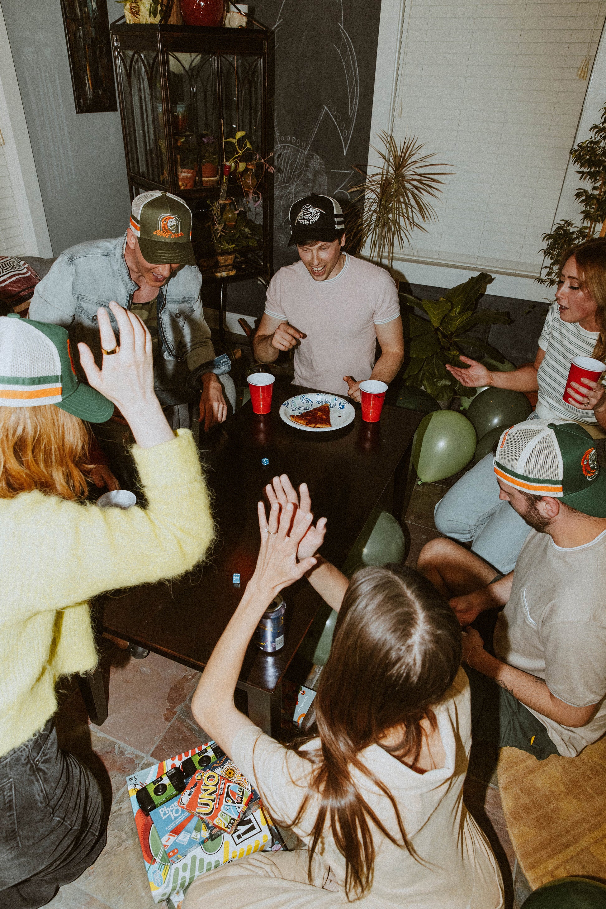 lifestyle image of friends playing a game, features multiple hats