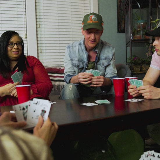 lifestyle video, friends playing a card game, features come home hat